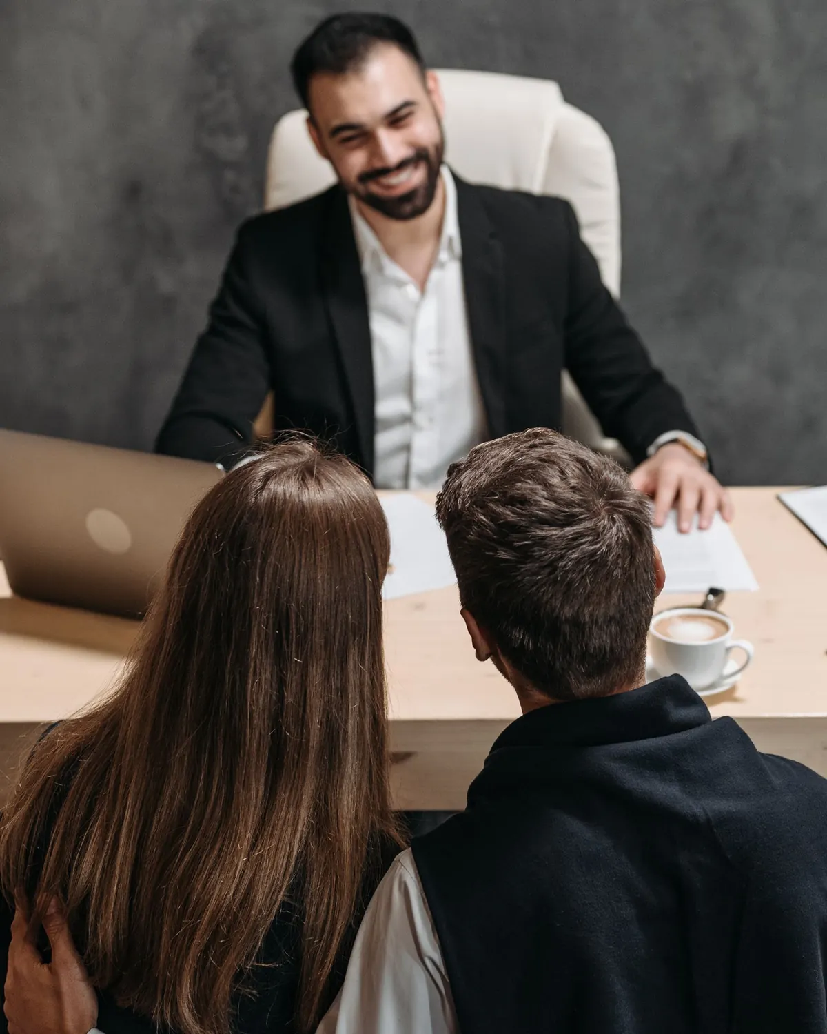 A Bestax consultant talking across a desk with a couple, an application form and a laptop open between them.