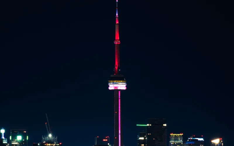 The CN Tower lit red, standing over the Toronto skyline at night.