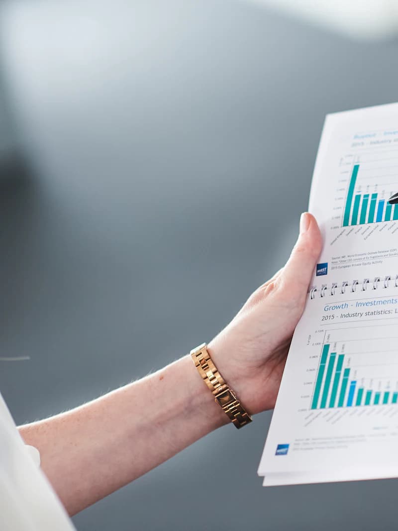 A hand holding a printed set of financial statements with industry performance charts on them.
