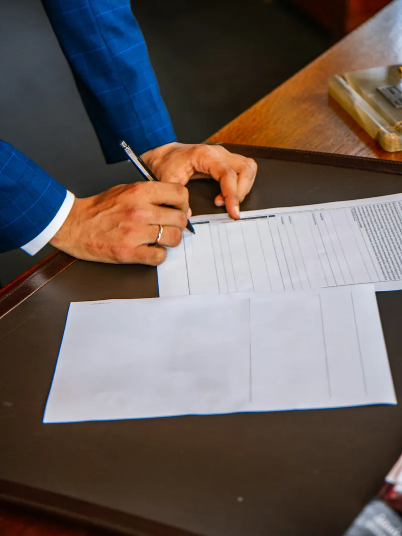 A pen poised over licence application paperwork on an office desk.