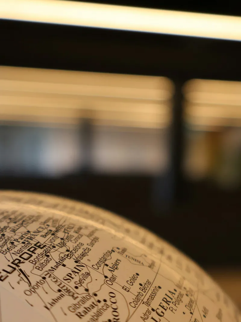 A desk globe under warm office light, turned to the trading routes a UAE cross-border structure has to cover.