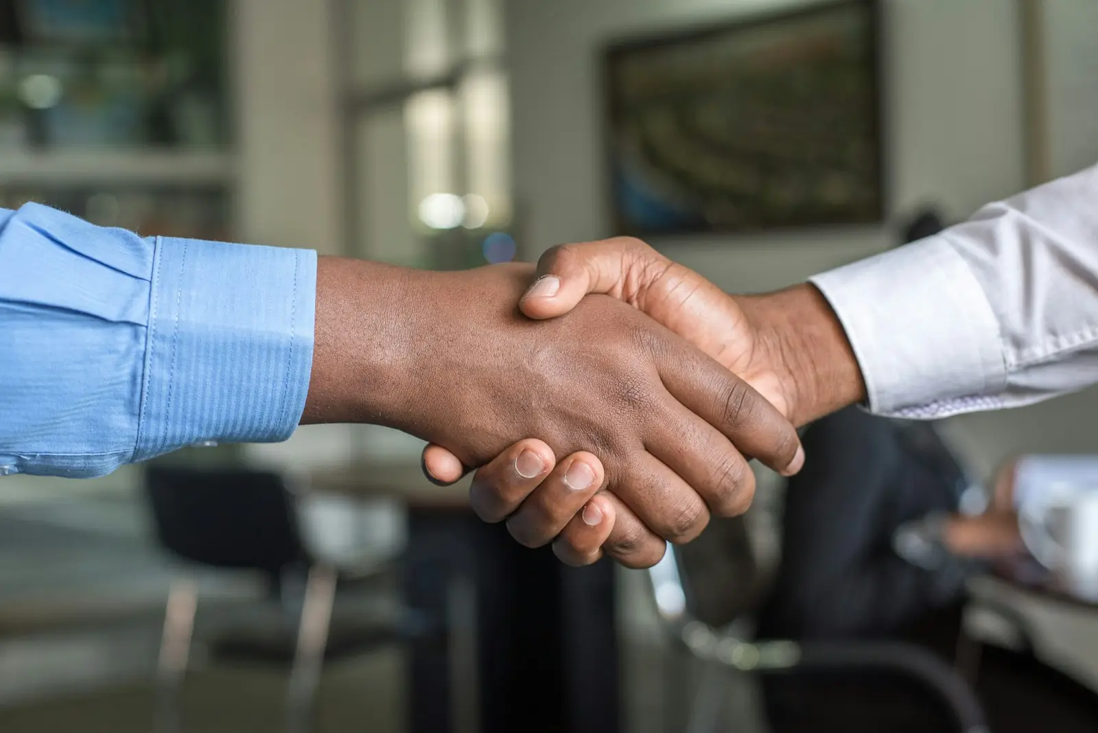 Two people shaking hands in an office meeting room.