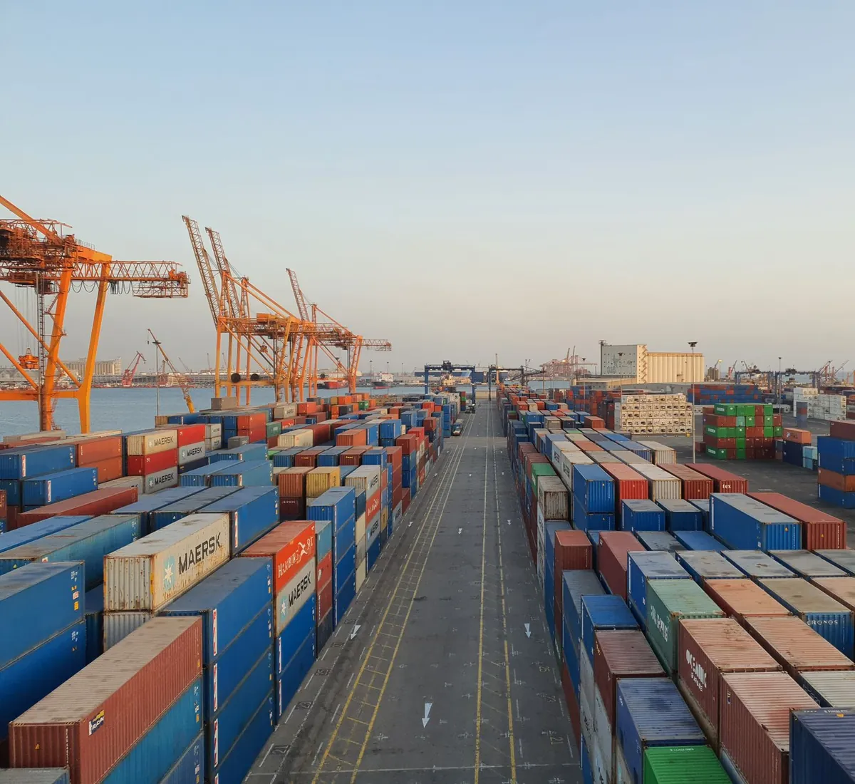 Rows of stacked shipping containers at a cargo terminal at sunrise