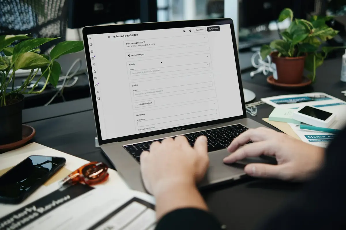 A finance professional editing an invoice in accounting software on a laptop.