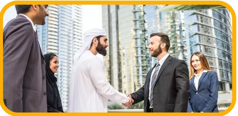 How to Start a Food Truck Business in Dubai in 2025 4 Business professionals, including an Emirati man, shaking hands with skyscrapers in the background.