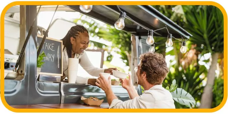 How to Start a Food Truck Business in Dubai in 2025 1 A food truck employee serving a smiling customer outdoors.