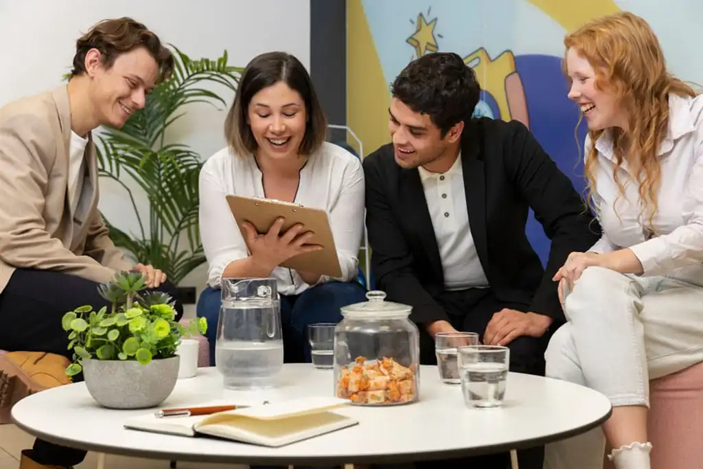 four people laughing while looking at something